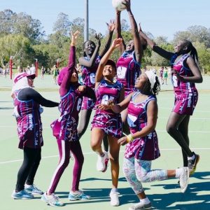 Refugee girls playing netball and jumping.